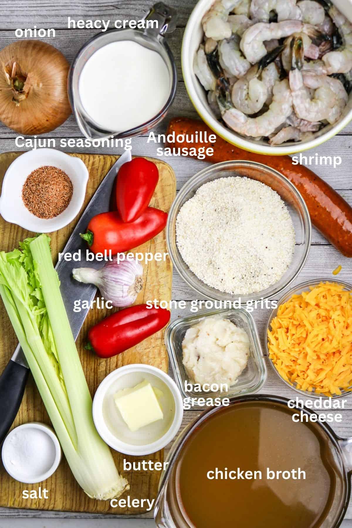 Ingredients of vegetables, shrimp, grits, cheese, and sausage on a board for Cajun Shrimp and Grits Recipe with Andouille Sausage.