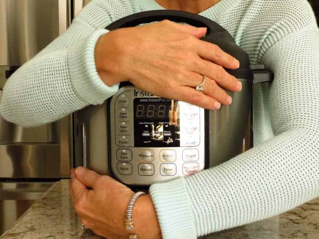 Two arms hugging an Instant Pot pressure cooker.