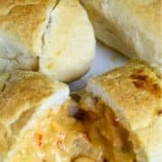 A Pinterest pin of a plate of crawfish pistolettes, bread rolls with cheesy crawfish sauce oozing out of a roll.