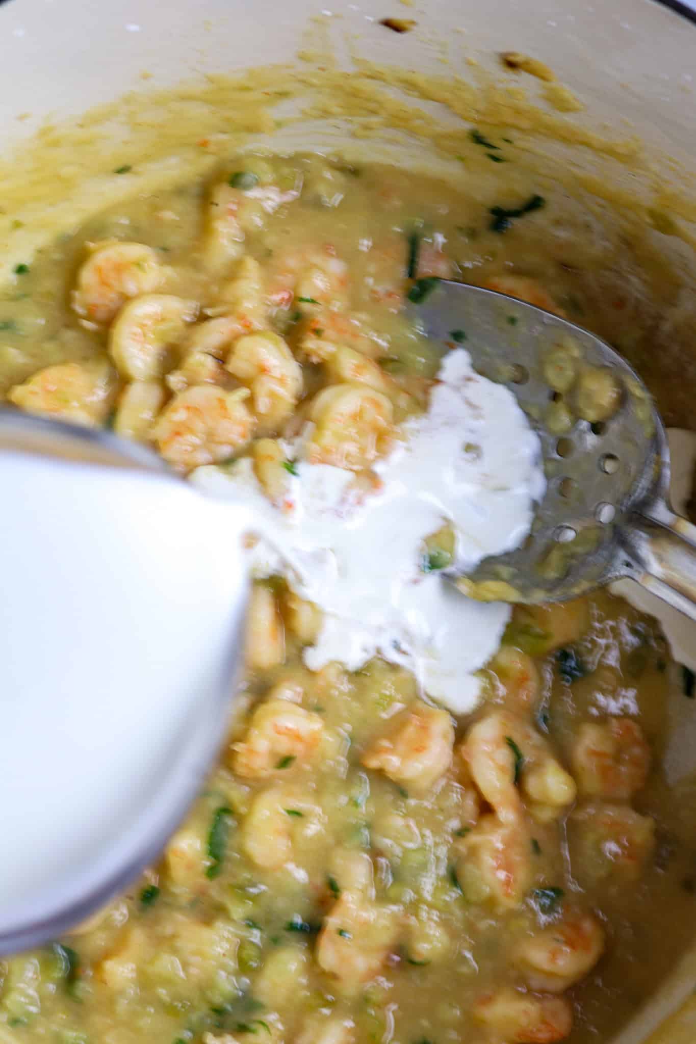 A pot of crawfish with a cup of cream pouring over it.