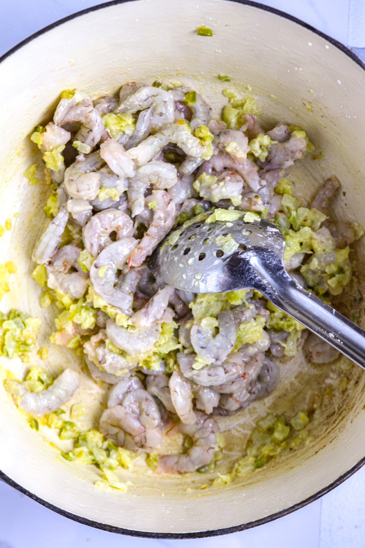 Raw shrimp in a white pot with onion in a butter for shrimp pistolettes.