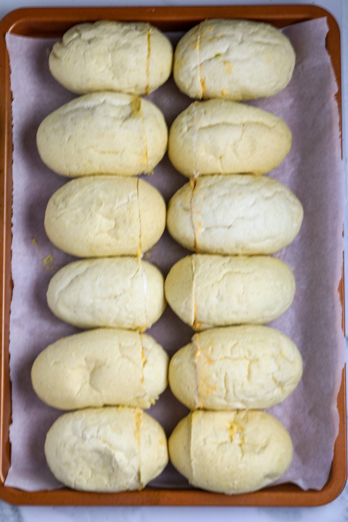 Twelve small rolls on a parchment-lined copper cookie sheet.
