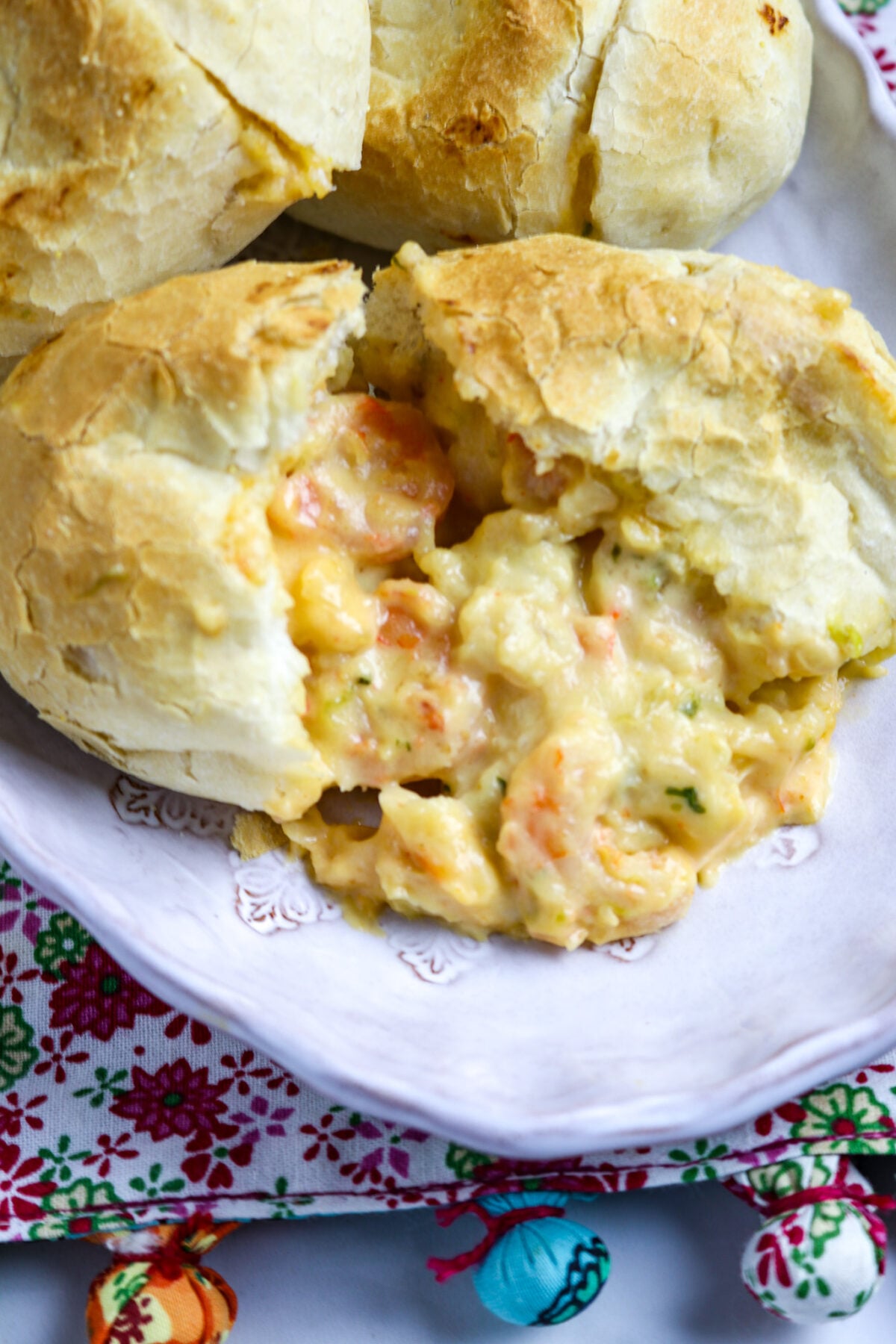 A pistolette on a plate cut in two with sauce coming out of the roll.