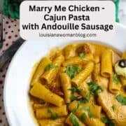 A white pasta bowl of chicken, pasta, sausage, in a luscious sauce sprinkled with chopped parsley.