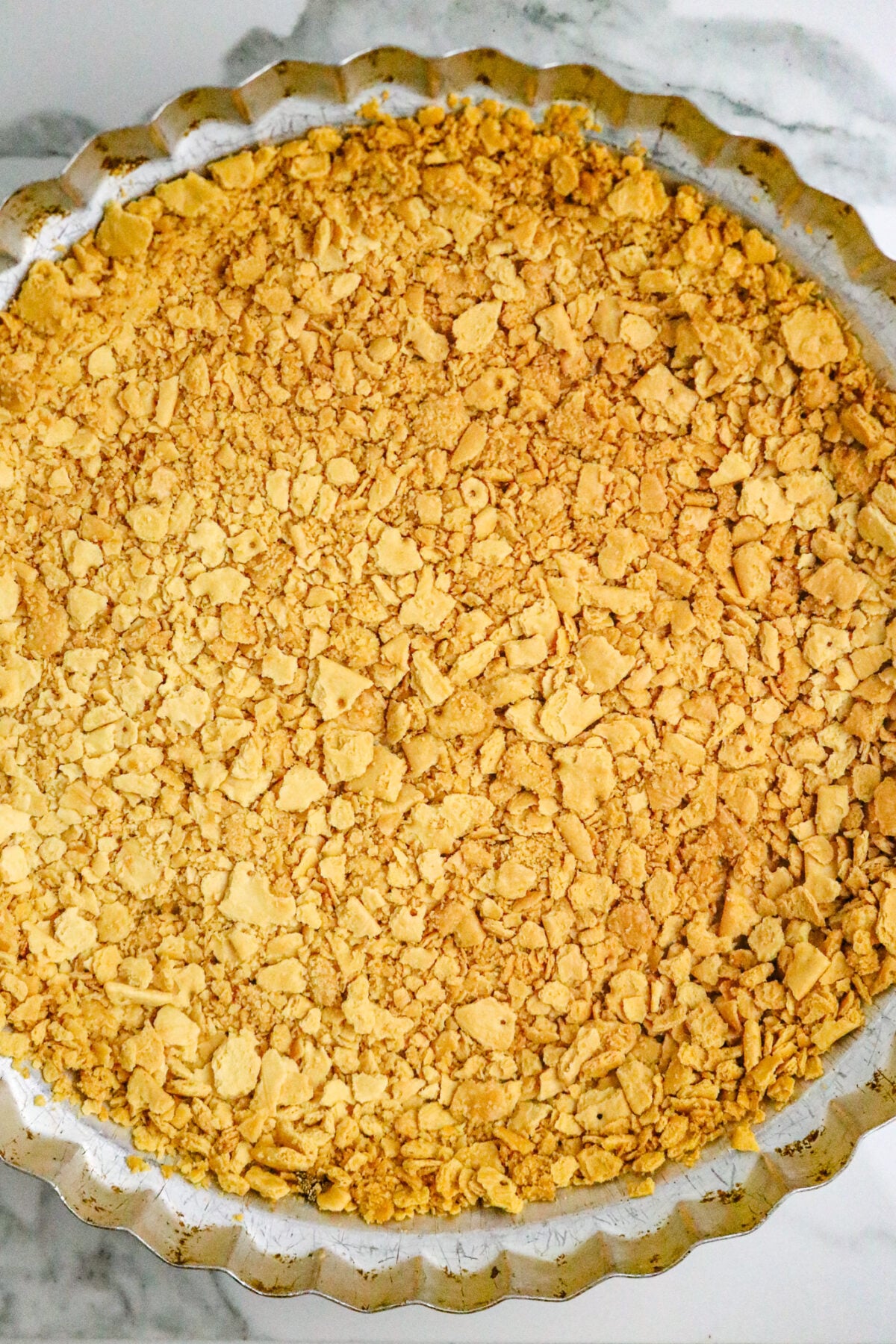 A browned saltine cracker pie crust in a metal pie plate.