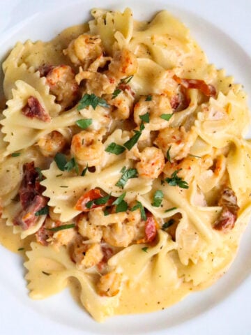 A serving of Marry Me Crawfish which is bowtie pasta in a cream sauce with crawfish in a white pasta bowl.