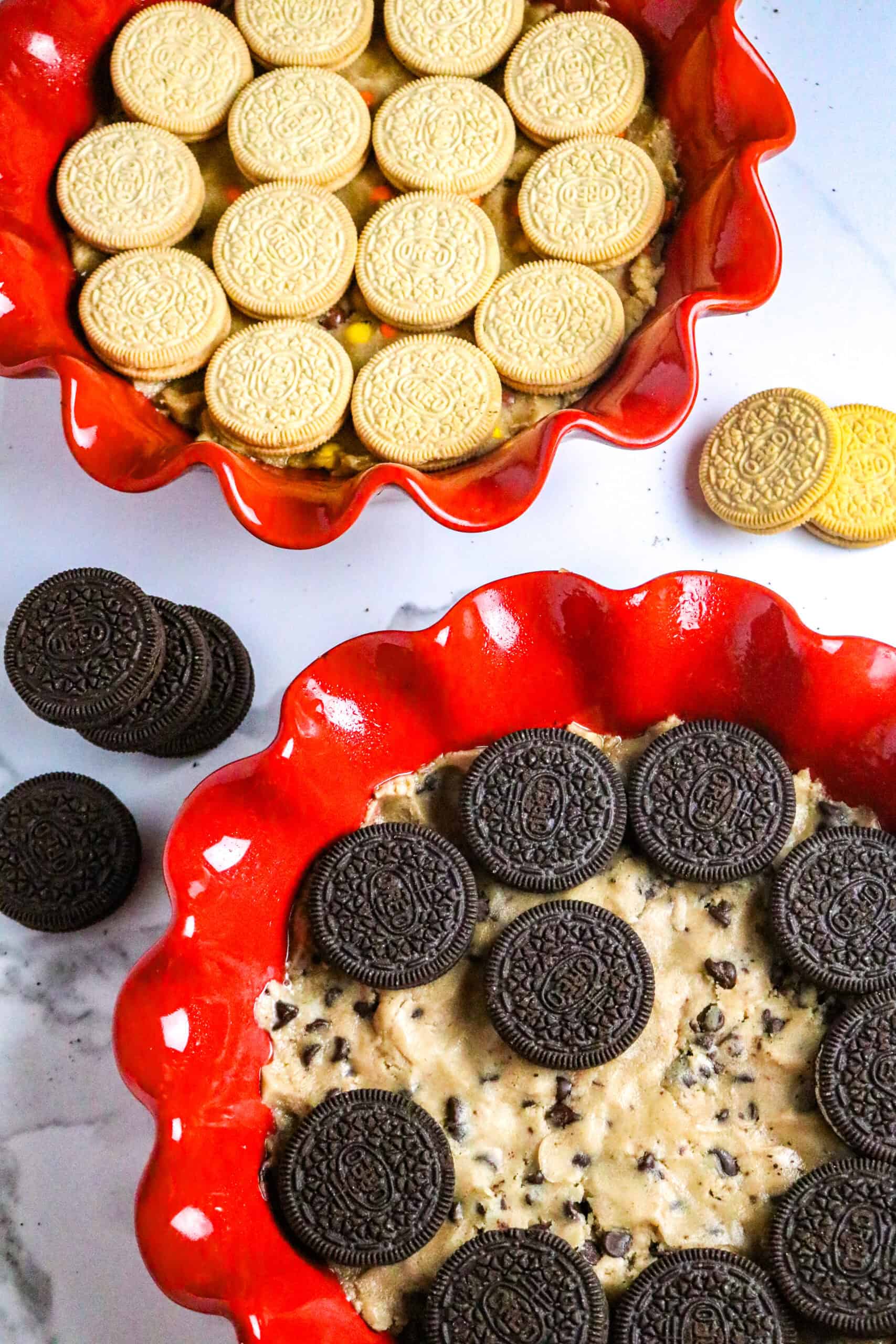 Two red pie plates lined wth cook dough and layered with vanilla and chocolate sandwich cookies.