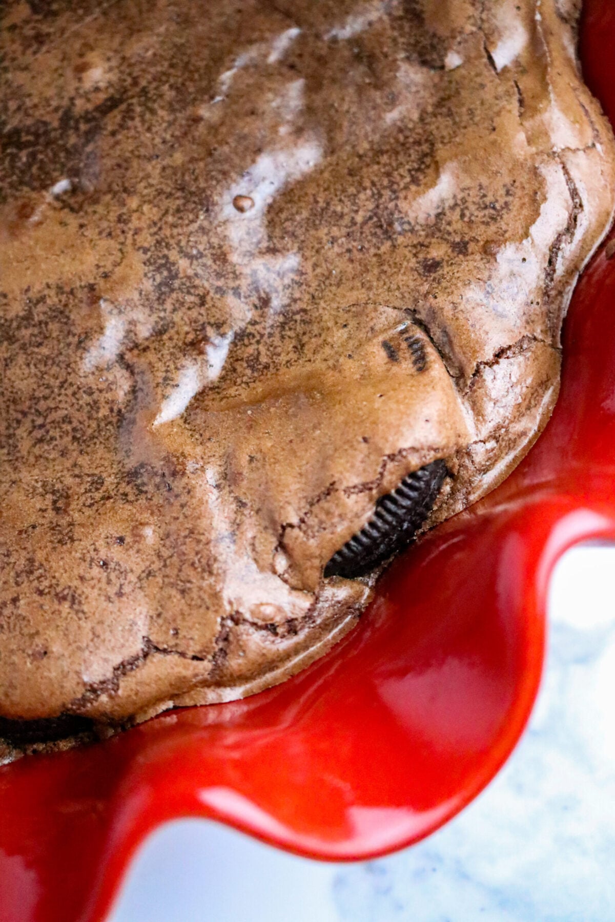 A chocolate pie with a brownie top and an Oreo cookie tucked in the outside edge in a red pie pan.